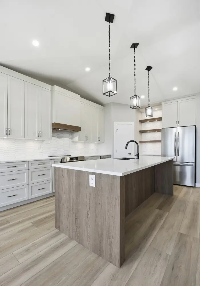 Modern kitchen cabinetry and island installation by 1st Coast Painting featuring sleek white cabinets, a wood-grain waterfall island, and stylish black pendant lighting.