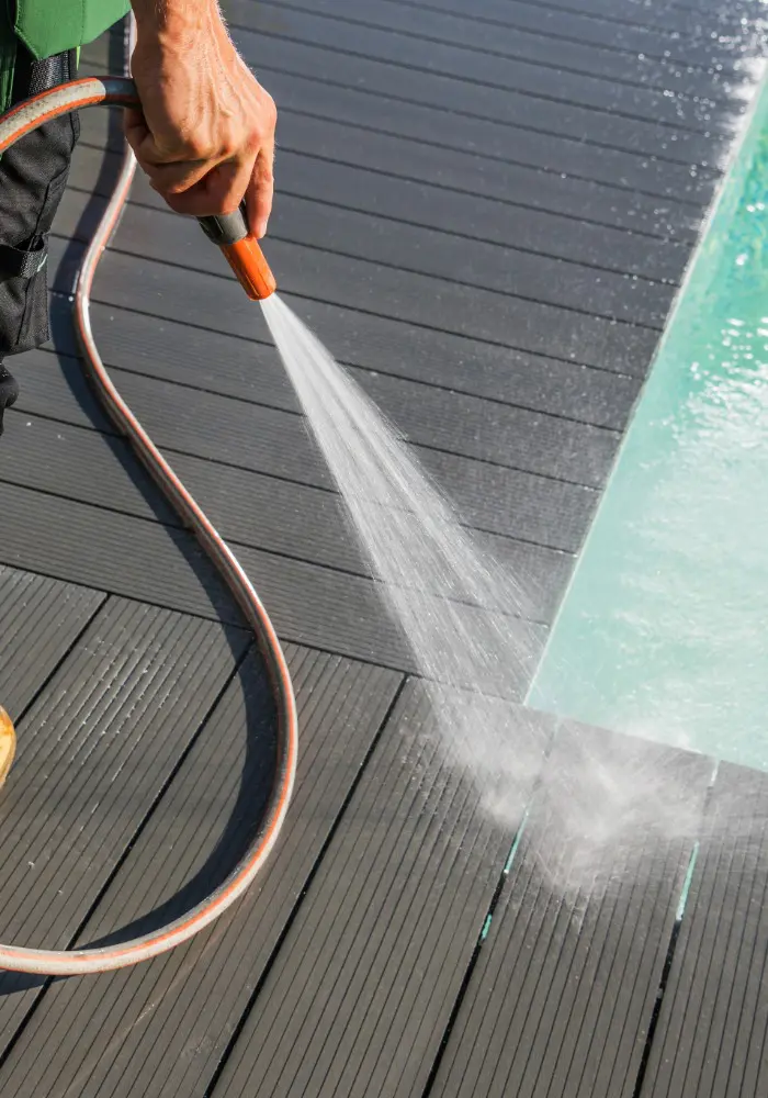 Professional 1st Coast Painting specialist meticulously power washing a modern grey composite pool deck to ensure a pristine surface.