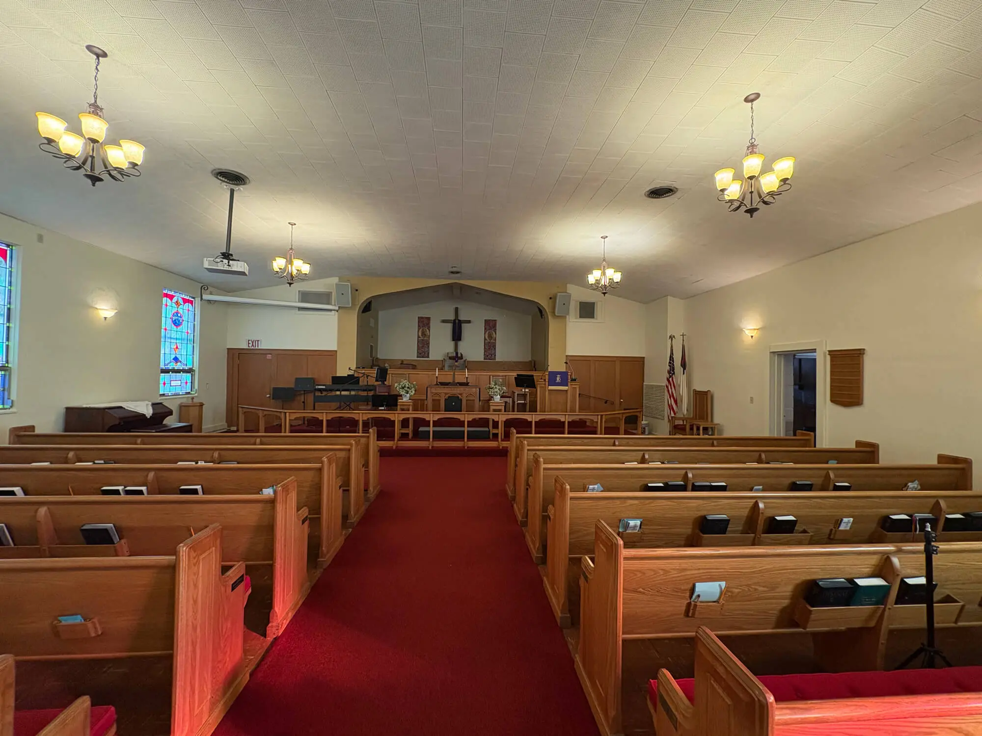 Professional interior sanctuary painting by 1st Coast Painting showcasing smooth cream walls, a vaulted ceiling, and warm wood pews in a traditional church.