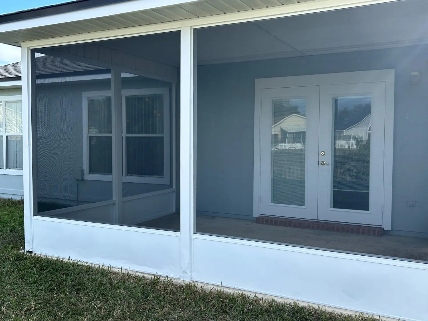 Residential screened-in back porch with crisp white trim and blue exterior walls revitalized by 1st Coast Painting services.