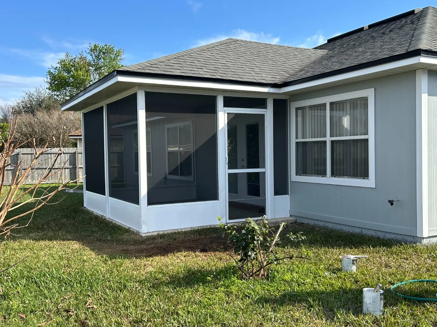 Professional screened-in patio and exterior siding refresh by 1st Coast Painting showcasing clean white framing, dark mesh, and matching trim on a light gray home.