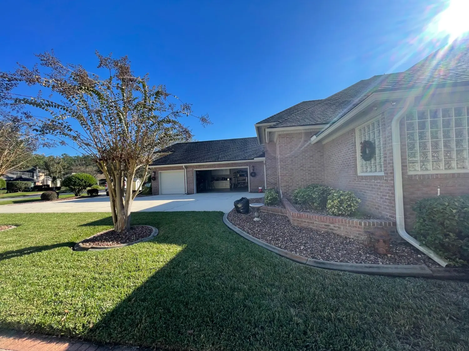 Premium exterior brick home transformation by 1st Coast Painting featuring clean white gutters and trim accents against a manicured landscape under a bright sunny sky.