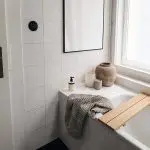 Clean white bathroom with tiled walls and bathtub showing how humidity affects bathroom paint and surfaces