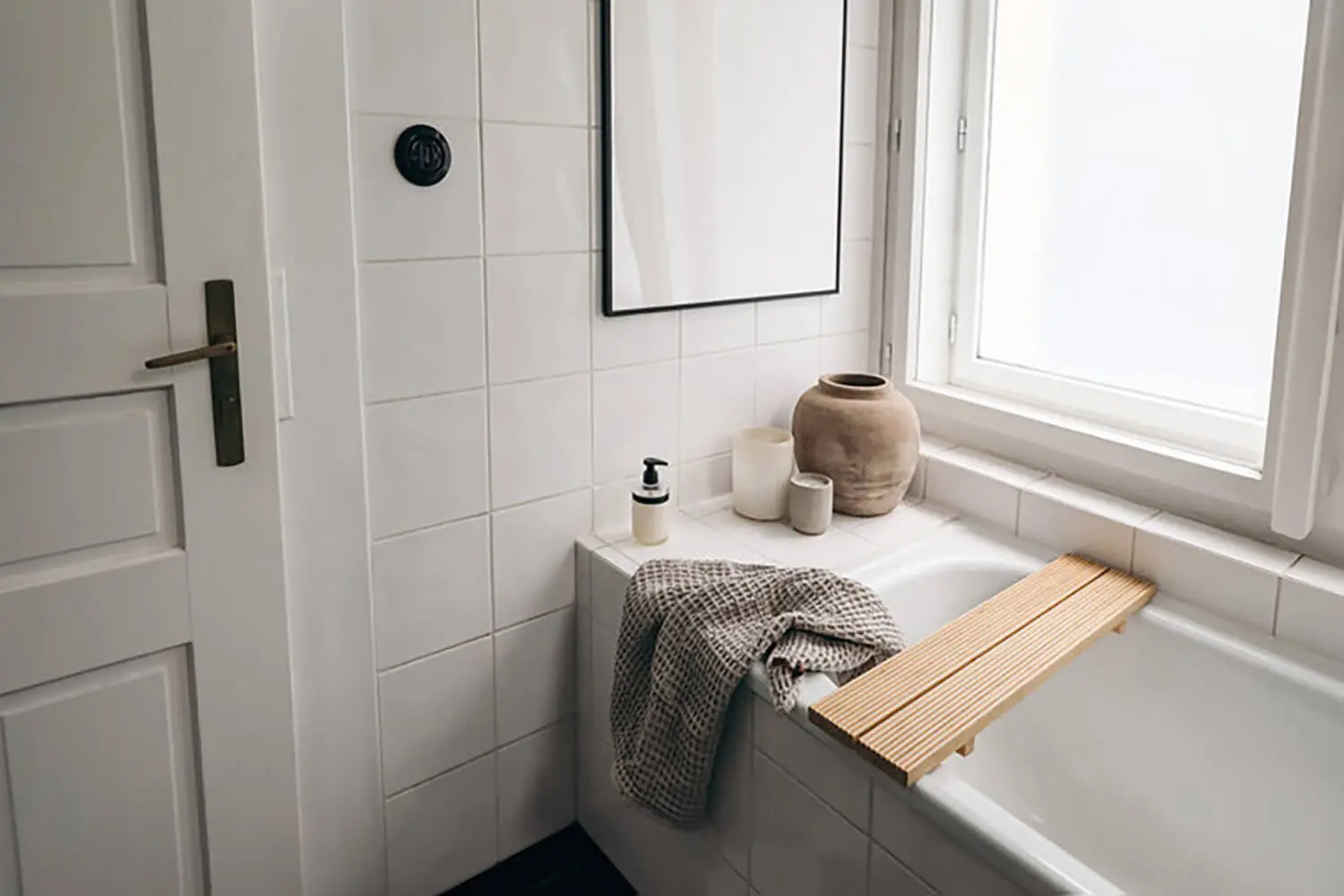 Clean white bathroom with tiled walls and bathtub showing how humidity affects bathroom paint and surfaces