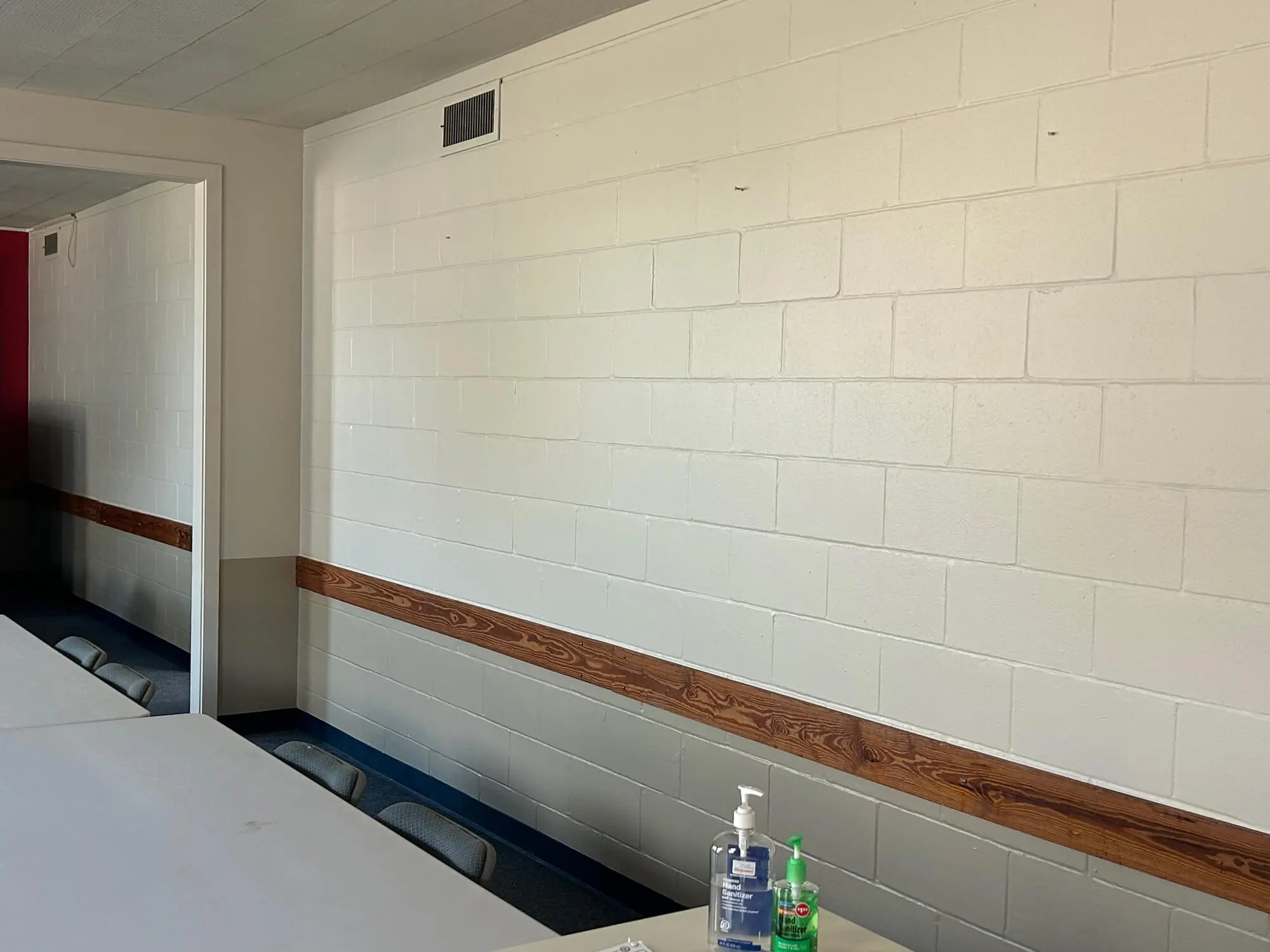Cream-colored cinder block wall with a natural wood chair rail accent in a clean commercial room, professionally maintained by 1st Coast Painting.