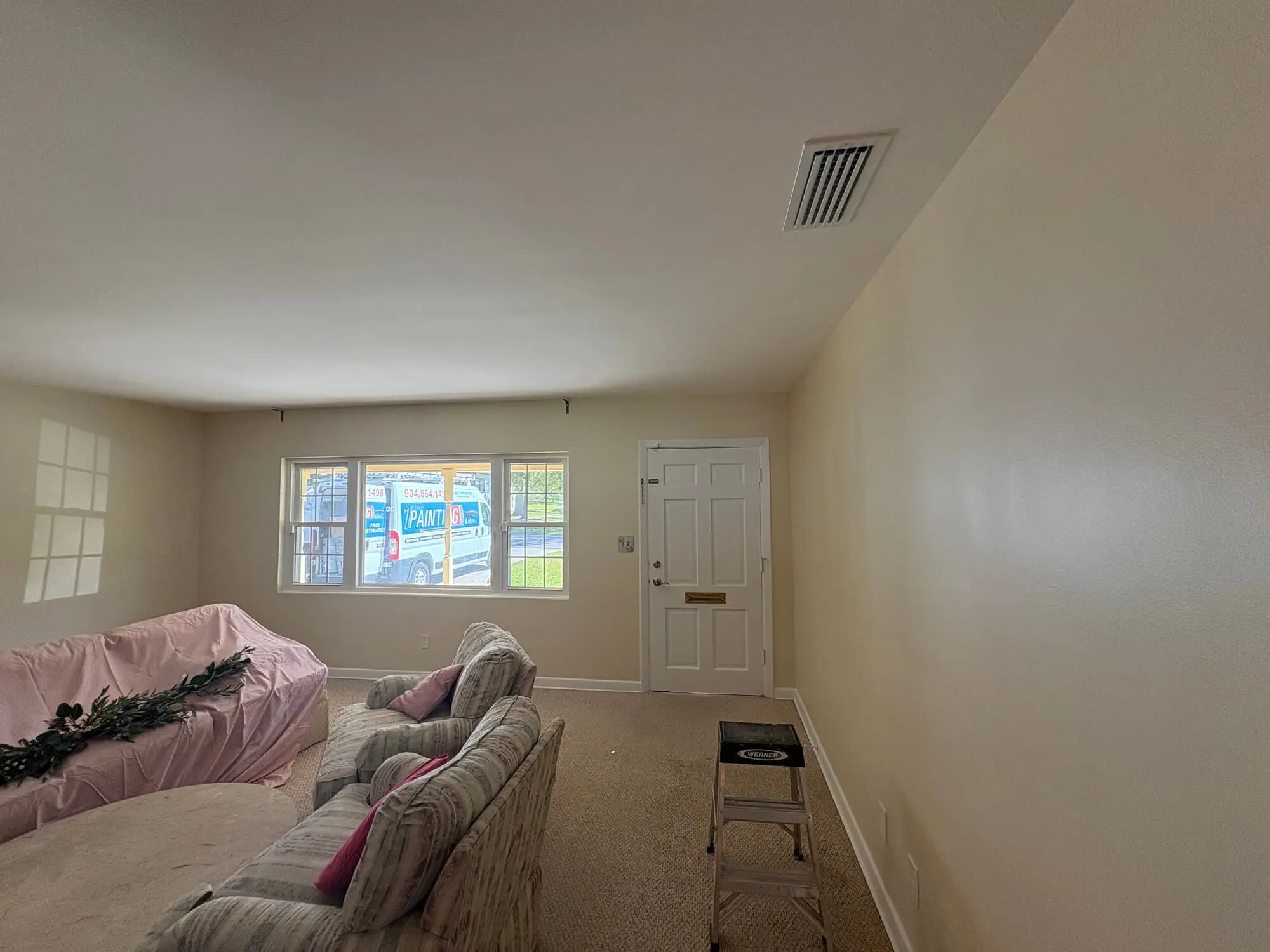 Residential living room interior featuring cream-colored walls and a white entry door expertly finished by 1st Coast Painting.