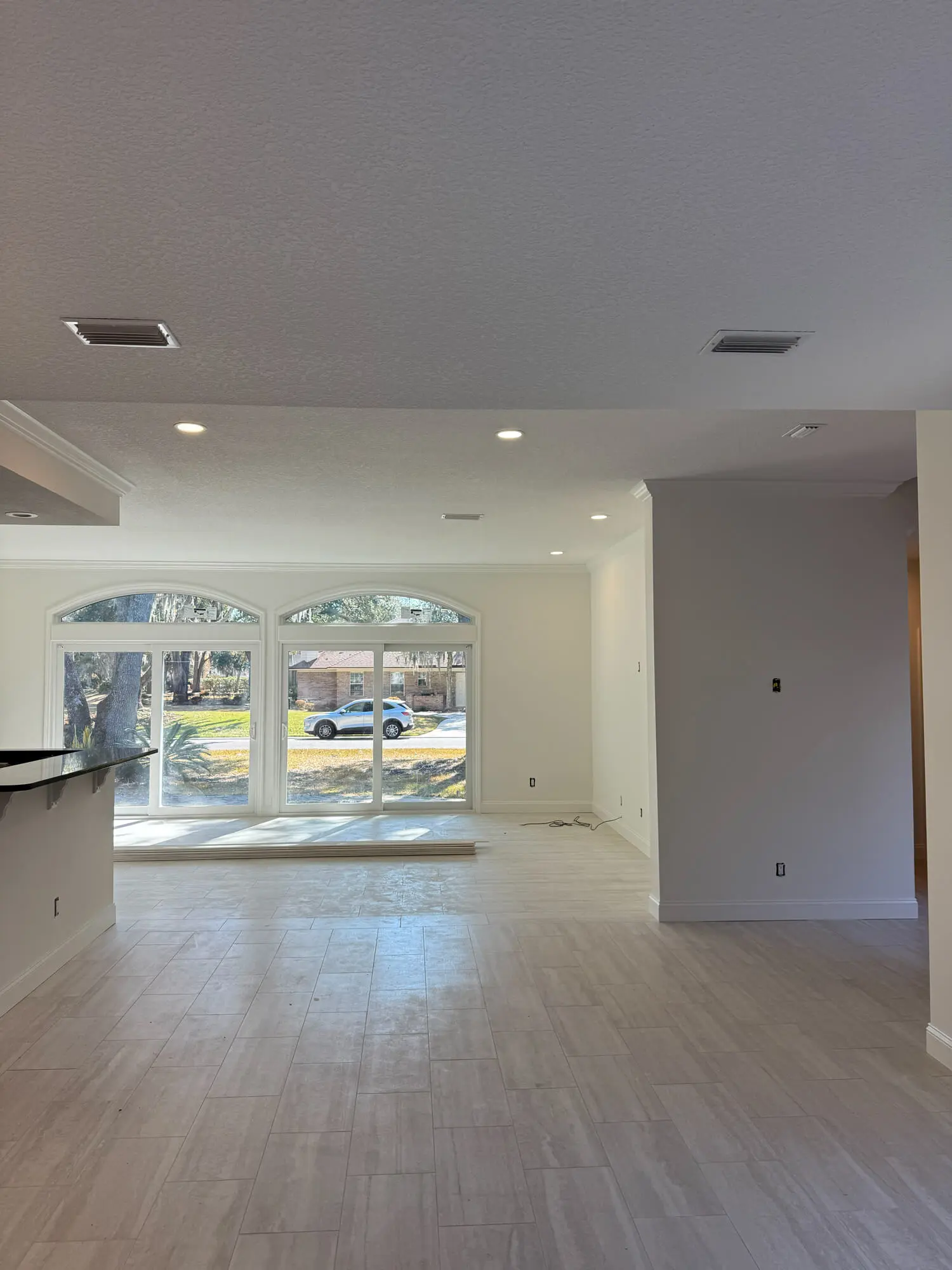 Freshly painted interior living space with arched sliding glass doors and neutral tile flooring, showcasing the professional finish of 1st Coast Painting.