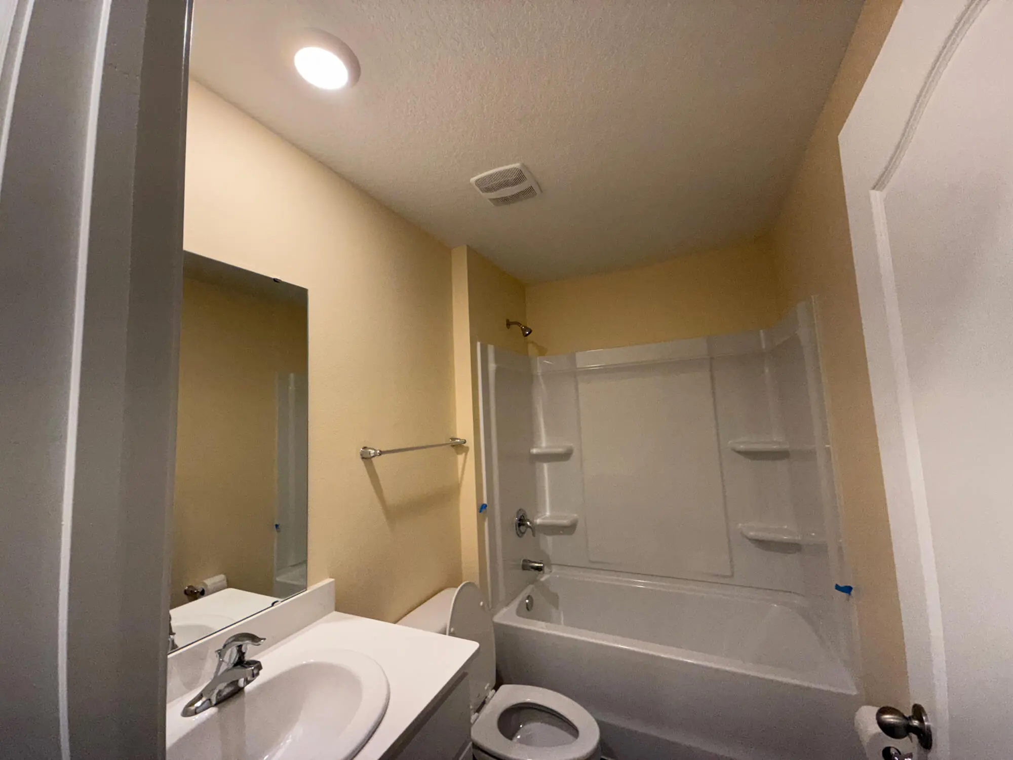 Professional bathroom renovation by 1st Coast Painting showcasing smooth cream-colored walls, clean white vanity, and a polished bathtub surround.