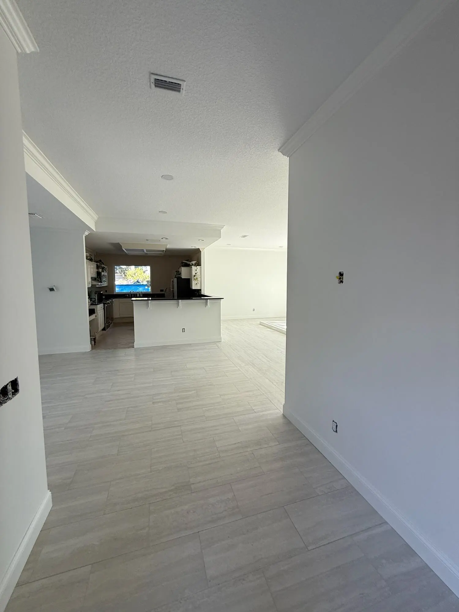 Freshly painted interior living space and kitchen featuring crisp white walls and crown molding completed by 1st Coast Painting.
