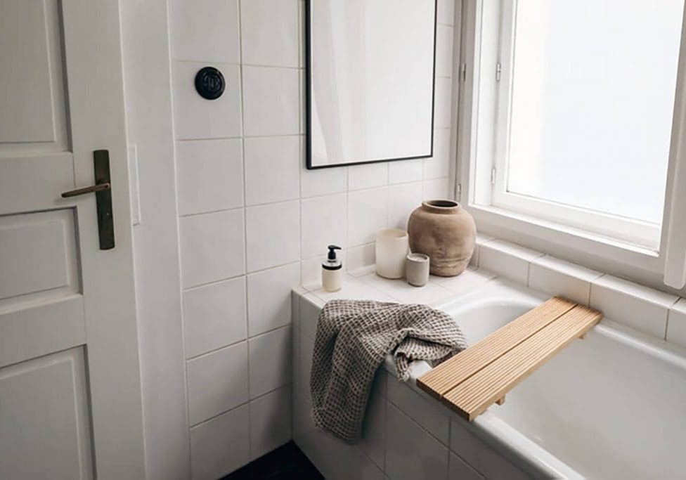 Clean white bathroom with tiled walls and bathtub showing how humidity affects bathroom paint and surfaces